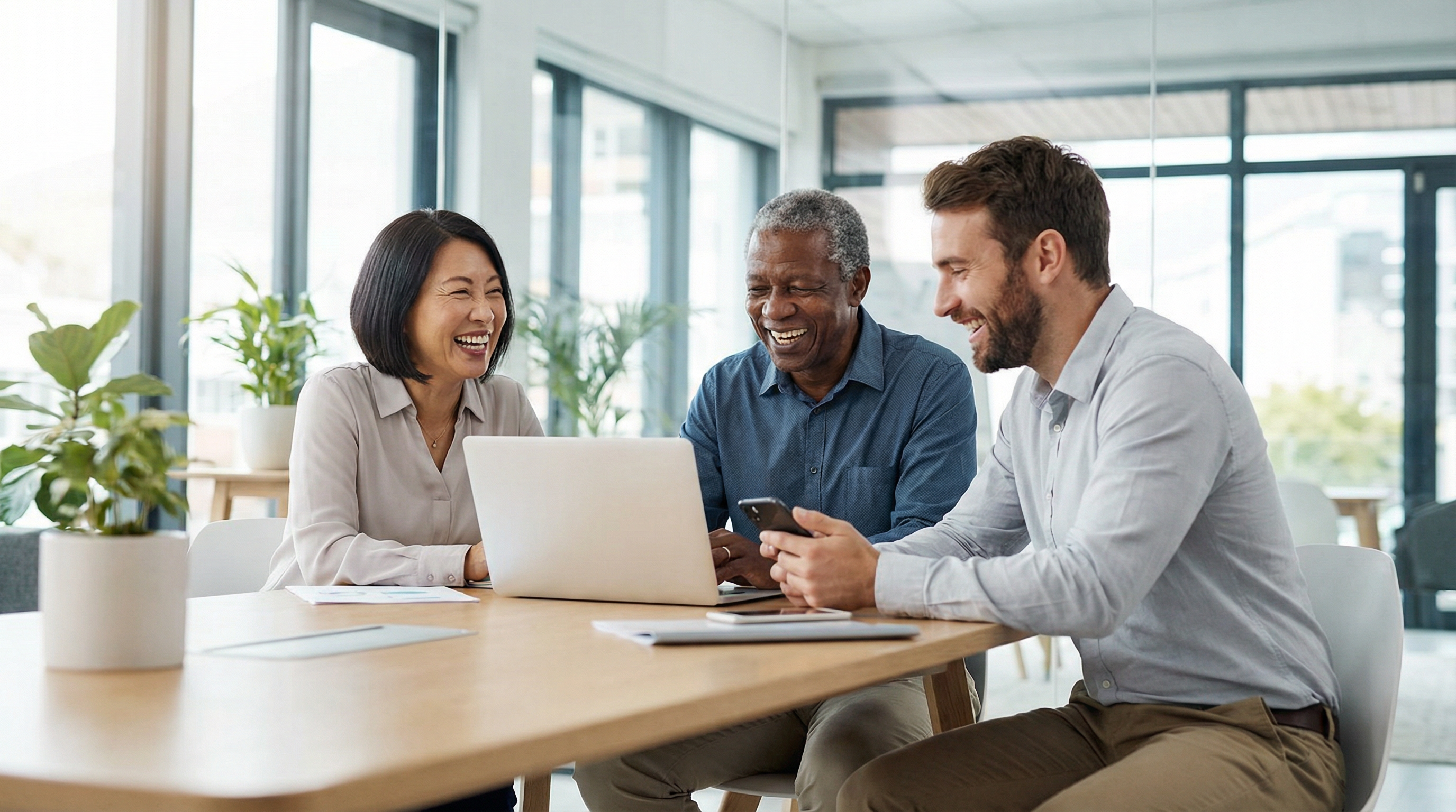 Diverse professionals collaborating with a laptop and smartphone